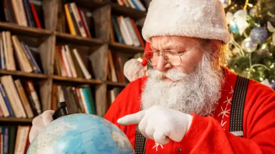 le Père Noël cherche une destination sur un globe.